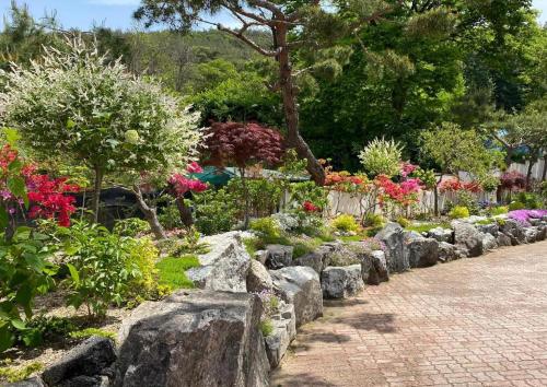 a garden with rocks and flowers and trees at Plain Hotel in Chuncheon