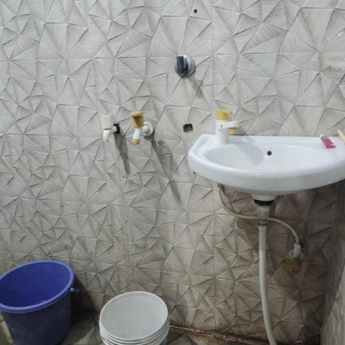 a bathroom with a sink and a tiled wall at Gaurangi dham in Mathura