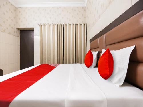 a bedroom with a bed with red and white pillows at Hotel O Behl Ashiana in Amritsar