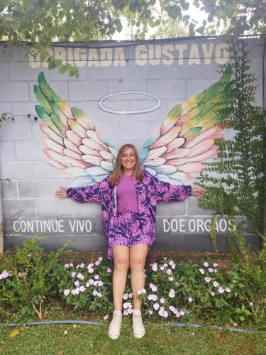 a woman standing in front of a sign with wings at POUSADA CHARLOTTE in Tiradentes