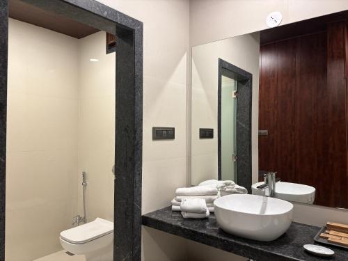 a bathroom with a sink and a toilet and a mirror at The Green Gate Resort Mulshi in Pune