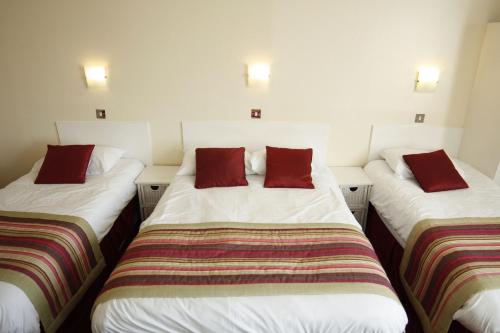three beds in a room with red pillows on them at Thanet Hotel in London