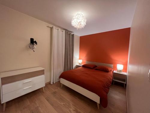 a bedroom with a bed with red walls and a chandelier at Terre ocrée in Ambérieu-en-Bugey