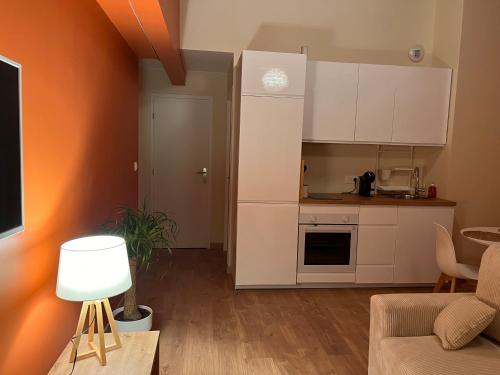 a kitchen with white cabinets and a living room at Terre ocrée in Ambérieu-en-Bugey