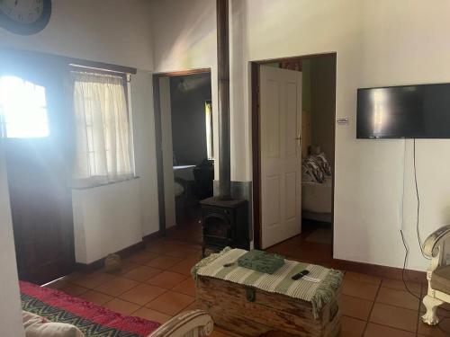 a living room with a table and a tv on the wall at Aan de Bergen in Swellendam