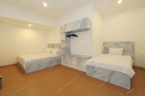 two beds in a room with white walls and wood floors at Villa Fiorenza II in Sampal 2