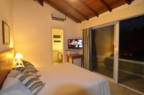 a bedroom with a white bed and a television at Pousada Dos Búzios in Búzios