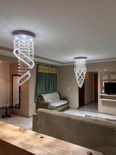 a living room with two chandeliers and a couch at Suíte por do sol 3 privada casa compartilhada in Xangri-lá