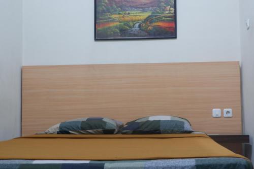 a bed with a wooden headboard in a bedroom at Hotel Taman Indah in Madiun