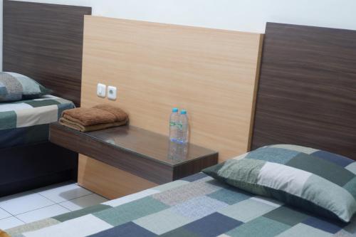 a bedroom with two beds and a table with a bottle on it at Hotel Taman Indah in Madiun