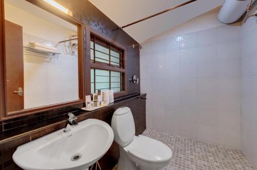 Un baño con un inodoro blanco y un lavabo. en Holiday Home Resort, en Kodaikanal