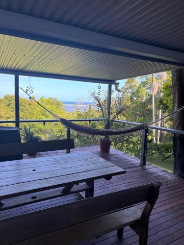 a wooden porch with a bench and a hammock at Sandbar views in Smiths Lake