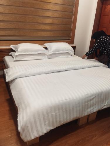 a large bed with white sheets and a wooden headboard at Equatorial Inn in Feydhoo