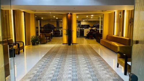 a lobby with yellow columns and a hallway with a rug at Hotel Kuber in Rāi