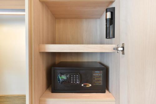 a microwave oven in a cupboard with a shelf at Centre Point Plus Hotel Pratunam in Bangkok
