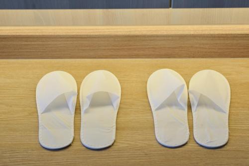a pair of white shoes sitting on a table at Centre Point Plus Hotel Pratunam in Bangkok