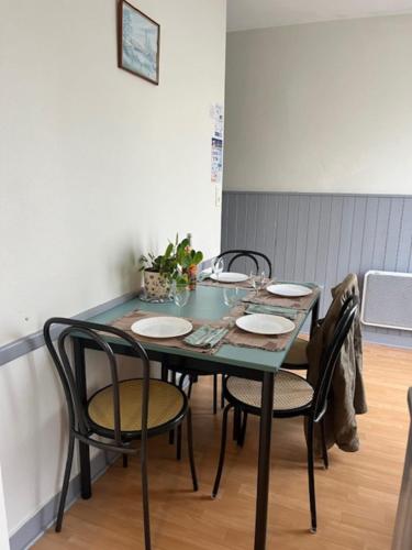 - une table à manger avec des chaises et des assiettes dans l'établissement 2 - Le Martin-Pêcheur - Village vacances, à Maché
