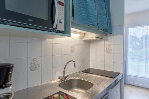 une cuisine avec un évier et un micro-ondes dans l'établissement 2 - Le Martin-Pêcheur - Village vacances, à Maché