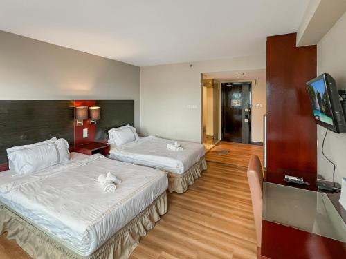 una camera d'albergo con due letti e una TV a schermo piatto di Royal Crown Scsp KK CBD near Imago a Kota Kinabalu