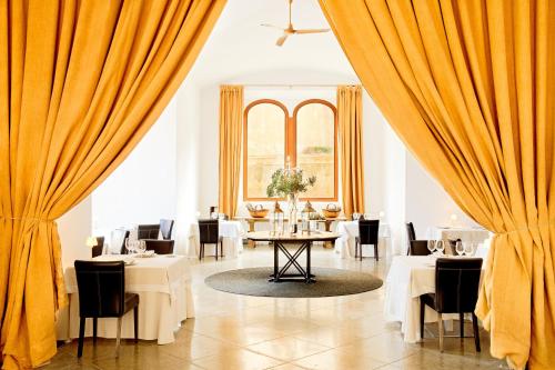 a restaurant with yellow curtains and tables and chairs at Cap Rocat, a Small Luxury Hotel of the World in Cala Blava