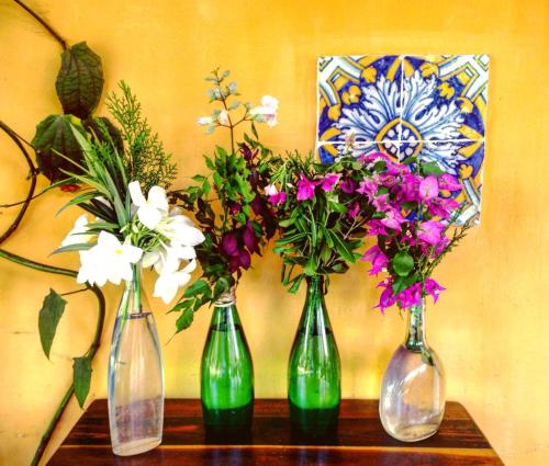 three vases with flowers in them sitting on a table at Villa Albergaria in Flecheiras