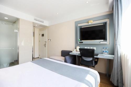 a hotel room with a bed and a desk and a tv at Zsmart智尚酒店上海南京西路梅陇镇广场店 in Shanghai