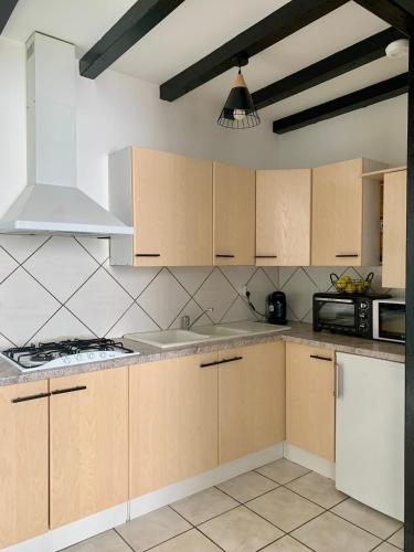 une cuisine avec des armoires en bois et un four à plaques de cuisson dans l'établissement PYRENE HOLIDAYS - Héraclès - Résidence paisible à 6mn à pied des thermes, à Bagnères-de-Bigorre