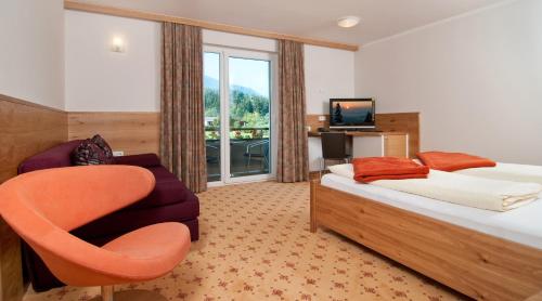 ein Hotelzimmer mit einem Bett und einem Stuhl in der Unterkunft Erlebnis-Hotel-Appartements in Latschach ober dem Faakersee