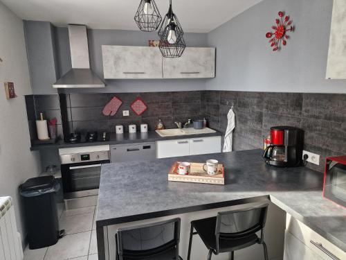 - une cuisine avec un comptoir et quelques chaises dans l'établissement Logis du Puits Salé, à Charmoille