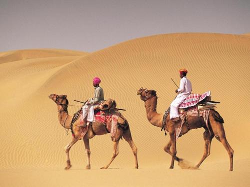 two people riding on camels in the desert at Arman Desert Luxury Camp & Resort Jaisalmer in Jaisalmer