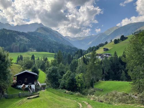 a house in a field with mountains in the background at Ferienhaus Wassermühle in Maria Luggau