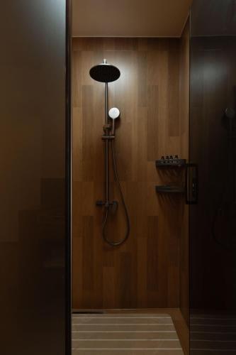 a shower in a bathroom with a wooden wall at Dali Lark View Private Hot Spring Hotel in Dali