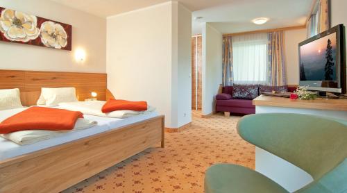 a hotel room with a bed and a couch at Erlebnis-Hotel-Appartements in Latschach ober dem Faakersee