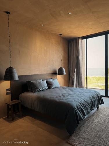 a bedroom with a large bed and a large window at inchantreedoolay huahin in Pran Buri