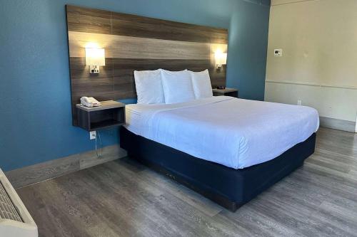a large bed in a hotel room with a phone at Days Inn by Wyndham San Diego Vista in Vista