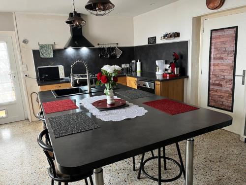 une cuisine avec une table avec un vase de fleurs dessus dans l'établissement Joli logement proche du Mont Lozère, à La Vernarède