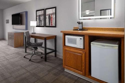 a hotel room with a desk and a microwave at AmericInn by Wyndham Iron Mountain in Iron Mountain