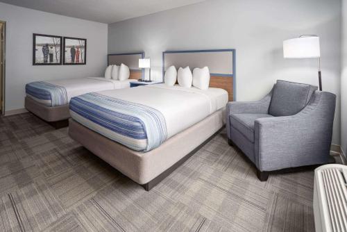 a hotel room with two beds and a chair at AmericInn by Wyndham Iron Mountain in Iron Mountain