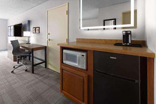 a kitchen with a microwave and a desk in a room at AmericInn by Wyndham Iron Mountain in Iron Mountain