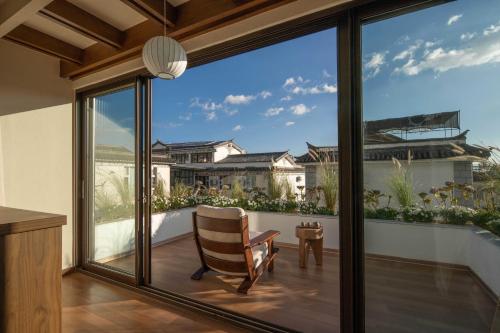 a room with large windows and a chair on a balcony at Dali Lark View Private Hot Spring Hotel in Dali