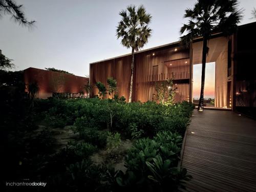 a building with palm trees and a wooden walkway at inchantreedoolay huahin in Pran Buri