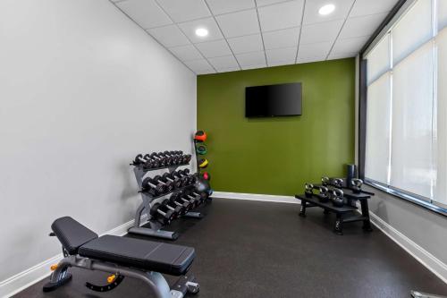 a gym with a green wall and a row of tread machines at Spark By Hilton Bensalem Philadelphia in Bensalem