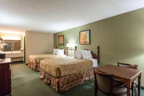 ein Hotelzimmer mit zwei Betten und einem Tisch in der Unterkunft Angel Inn Near IMAX, a Travelodge by Wyndham in Branson