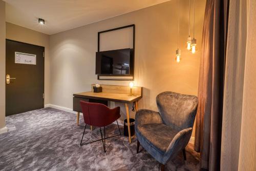 a room with a desk and a chair and a mirror at Vienna House Easy by Wyndham Bonn City in Bonn