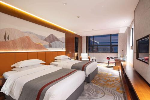 a hotel room with two beds and a television at Ramada Encore by Wyndham Jingzhou Shashi in Jingzhou