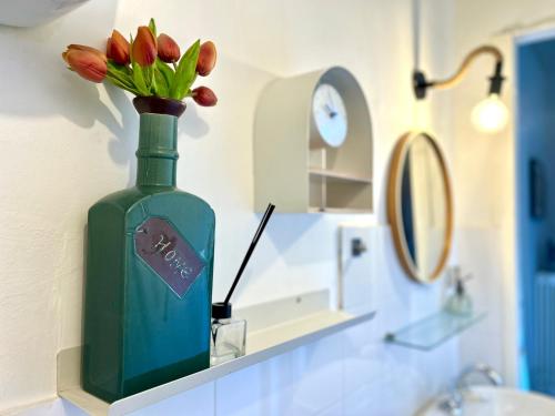 a green vase with flowers on a shelf in a bathroom at fattoria Coppetella Cemani in Molino dʼAgugliano