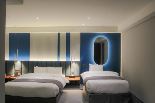 a hotel room with two beds and a mirror at Interburgo Hotel Wonju in Wonju