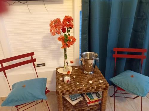 a table with a vase with flowers on it next to two chairs at Bungalow La Marina in Le Marin