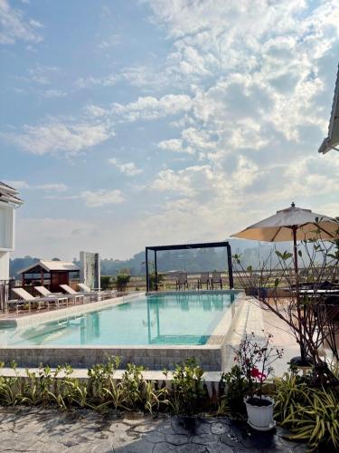 a large swimming pool with an umbrella on a building at Baan Marukome Chiang Rai บ้านมารุโกเมะ เชียงราย in Ban Pa Yang (3)