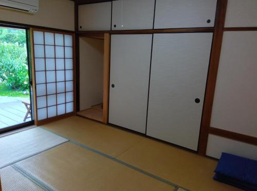 an empty room with white doors and a window at Akitsuki Kominka Yado You in Asakura